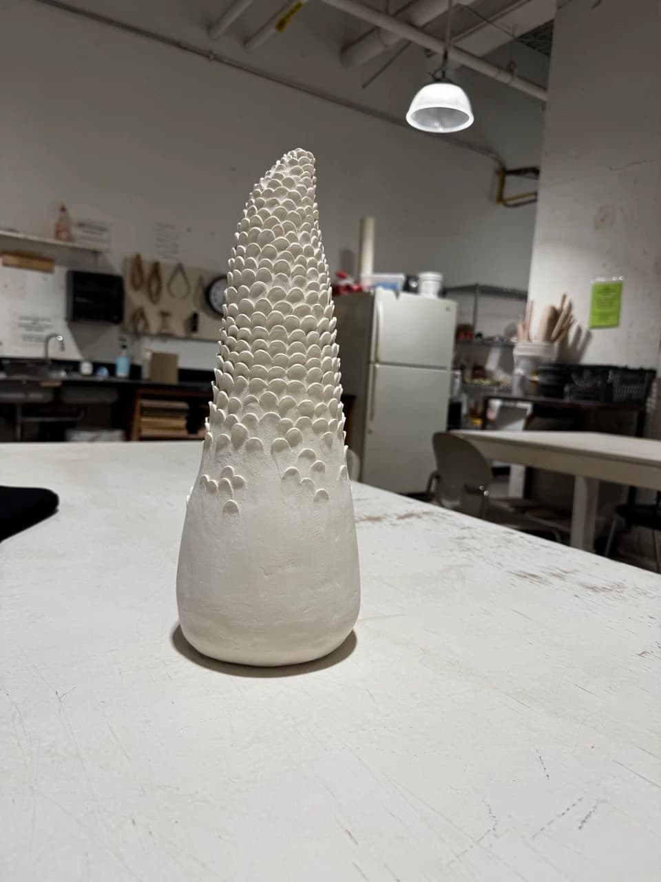 Pale ceramic cypress form before the finished glazed stage.