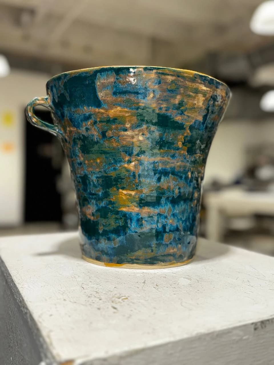 Finished blue and earthy glazed kashk-sab ceramic vessel with a handle.